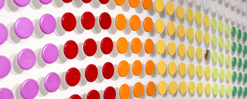 Färgprover av plastdetaljer i olika kulörer arrangerade i rader för visning av lackeringsmöjligheter.