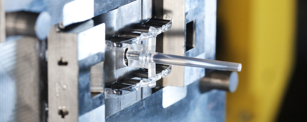 Närbild på en transparent plastkomponent i en formsprutningsform. Den färdiga detaljen sitter kvar i verktyget efter formsprutning och visar tydligt kärnformen.