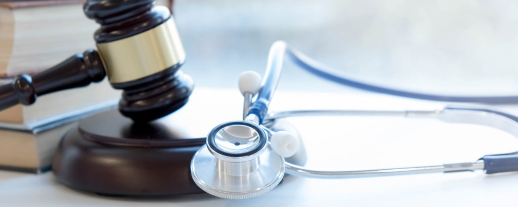 A gavel, a stethoscope, and books placed on a table, symbolizing medical law or healthcare regulation.