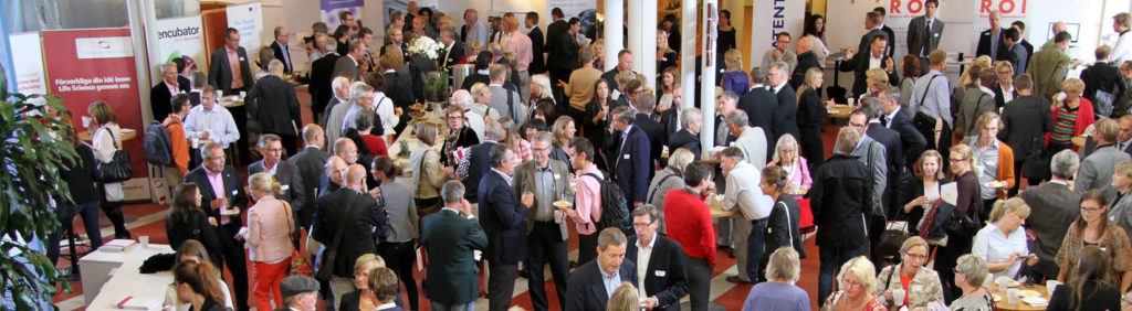 Människor minglar i en mässhall under ett event med fokus på life science och innovation, med utställarmontrar i bakgrunden.