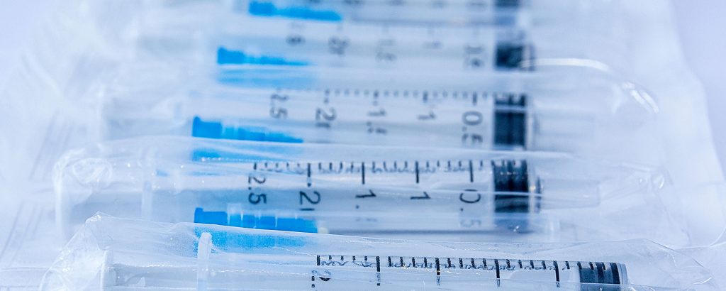 Rader av sterilt förpackade sprutor i plast – fokus på medicintekniska engångsartiklar och hygien.